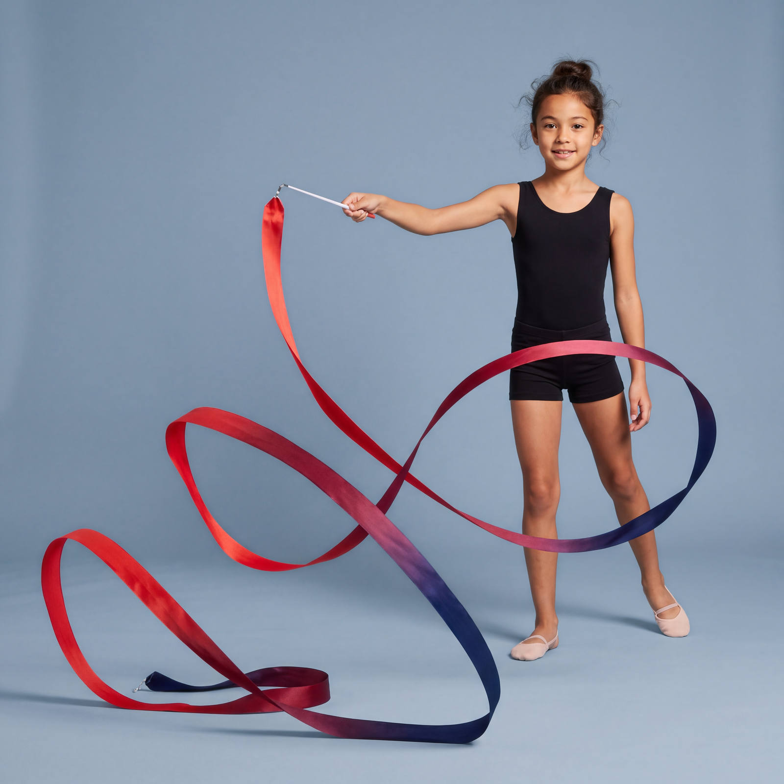 A young rhythmic gymnast standing with her ribbon sweeping in a long spiralling curve across the floor